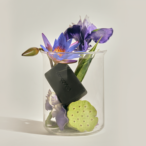 DONGGUBAT Field Blooming Perfume Shampoo Bar Calming 80g displayed in a clear jar with purple and green floral arrangement.
