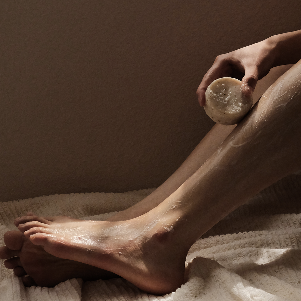 Person using DONGGUBAT Field Correct Body Soap Noni on leg for skincare.
