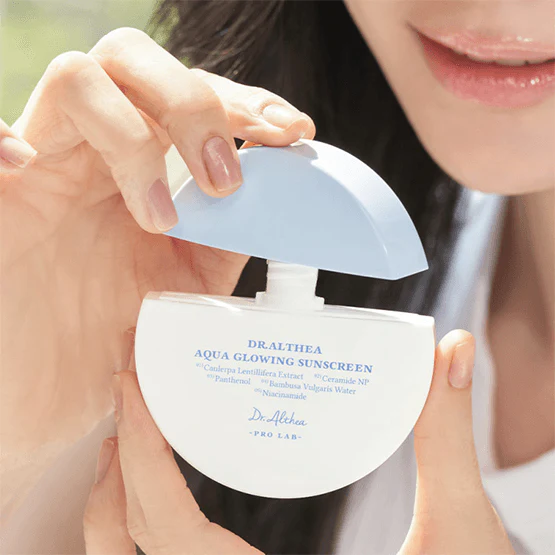 Person opening a bottle of DR.ALTHEA Aqua Glowing Sunscreen 45ml in natural light.