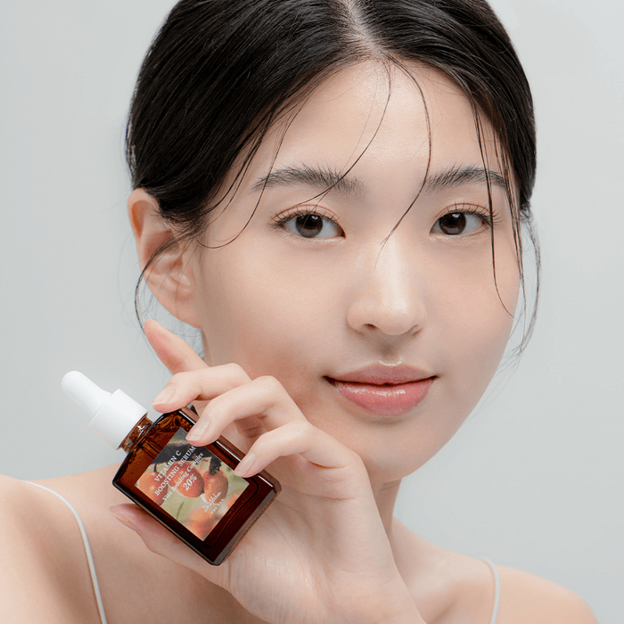 Person holding bottle of DR.ALTHEA Vitamin C Boosting Serum 30ml with clear skin.