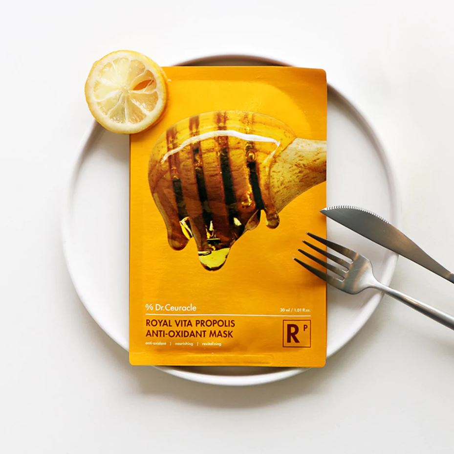 DR.CEURACLE Royal Vita Propolis Glow Mask (10EA) displayed on a white plate with a lemon slice and cutlery.