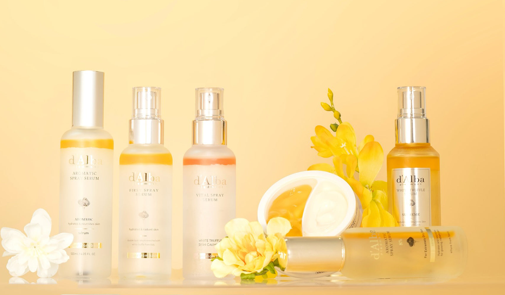 Luxury skincare products displayed with fresh flowers and sliced lemon on a yellow background.