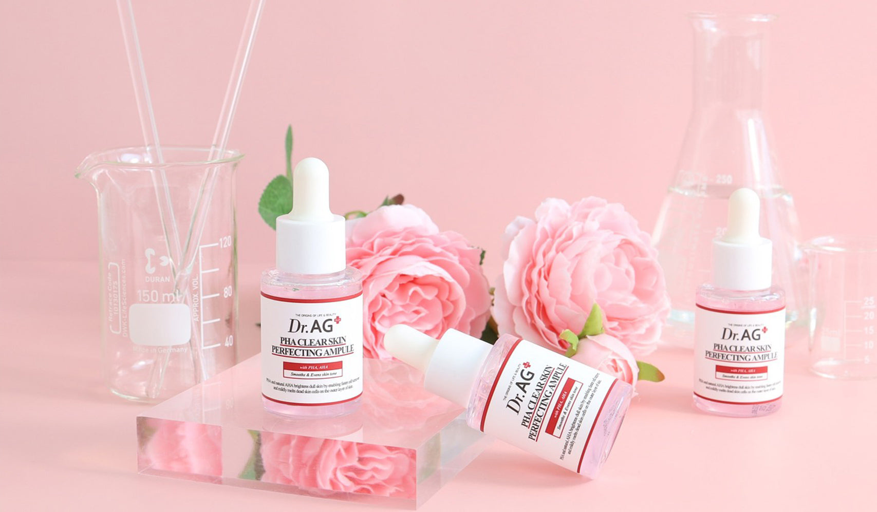 Dr. AG skincare product display with floral background, featuring glass beakers and pink roses for an elegant aesthetic.