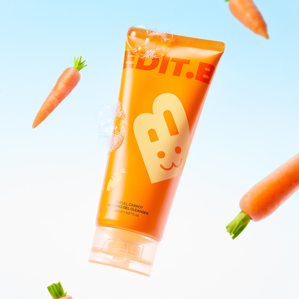 EDIT.B Joyful Carrot Foaming Gel Cleanser 150ml bottle surrounded by floating carrots on a light blue background
