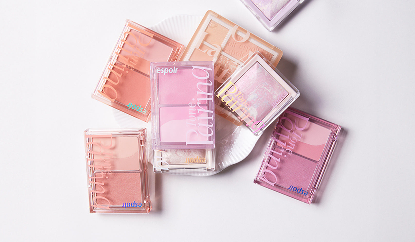 Assorted espoir makeup palettes in pink and peach hues on a white background, showcasing beauty products.