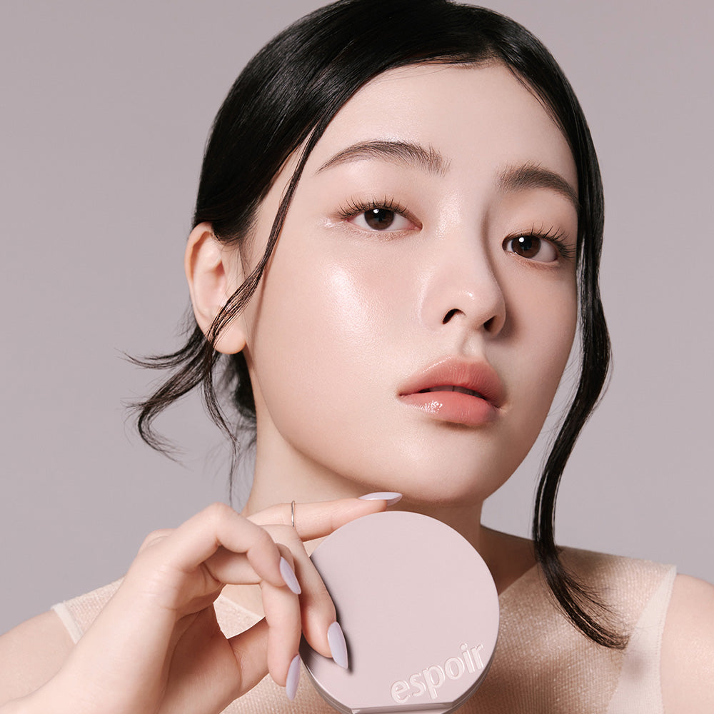 Woman holding ESPOIR Be Natural Cushion SPF50+ PA++++ showcasing radiant skin