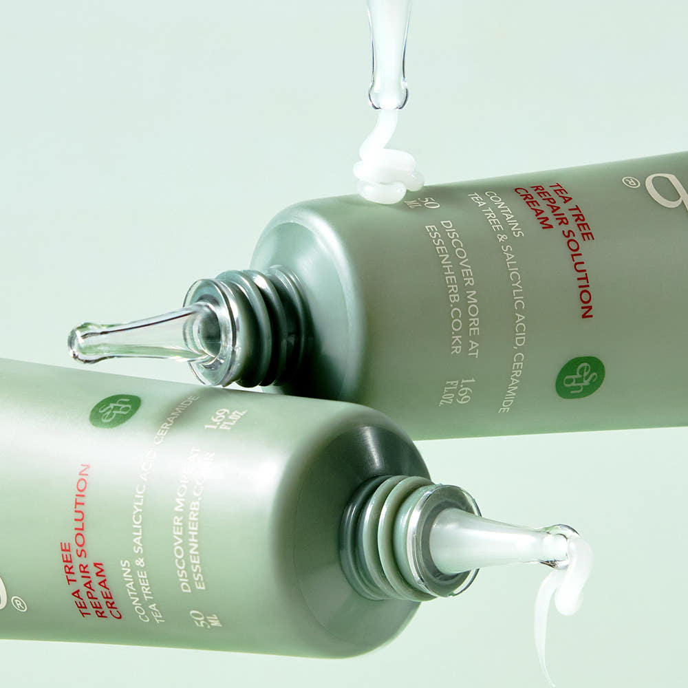 ESSENHERB Tea Tree Repair Solution Cream 50ml bottles dispensing product on green background
