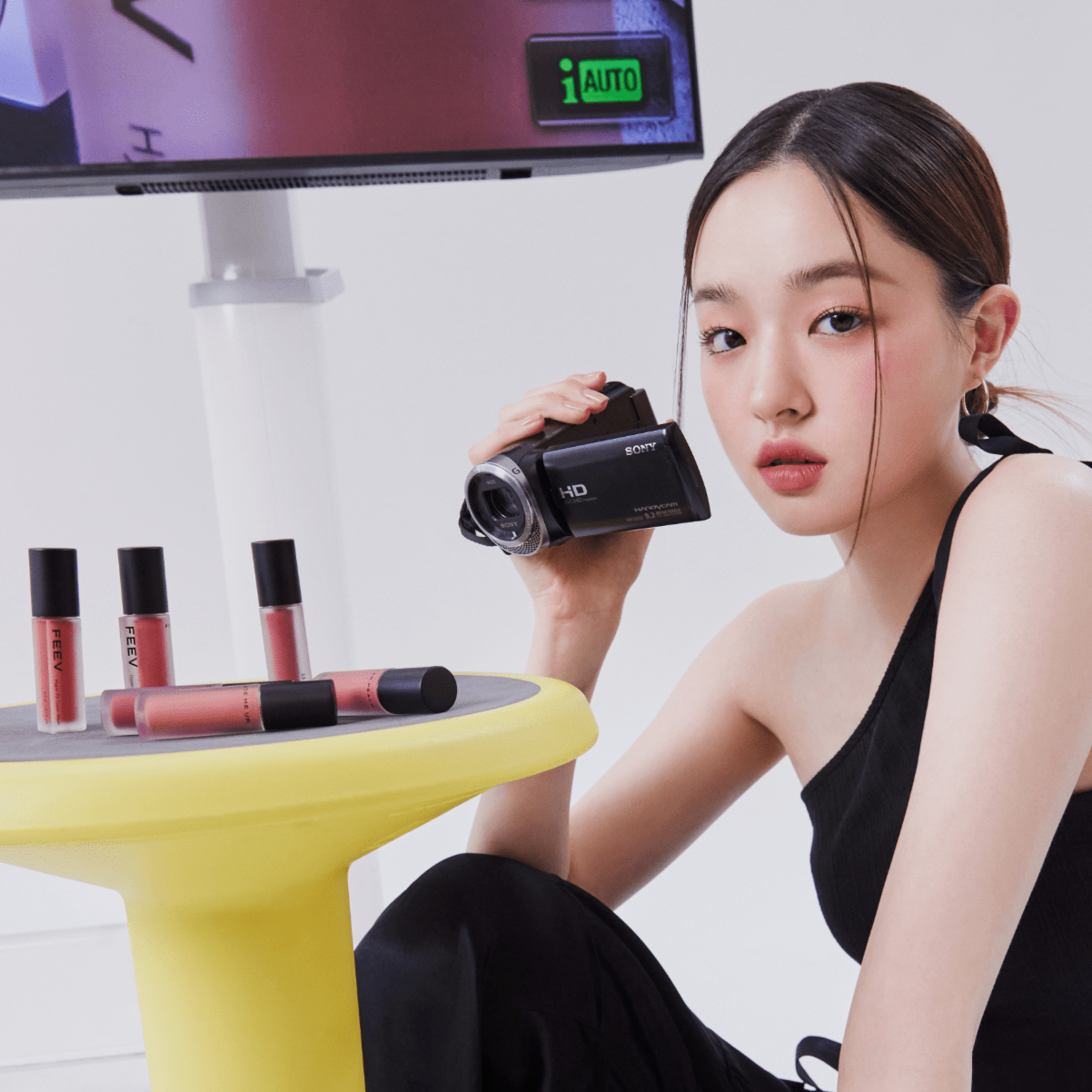 FEEV Hyper-Fit Color Wear Tint displayed with a model holding a camera, showcasing makeup application and style.