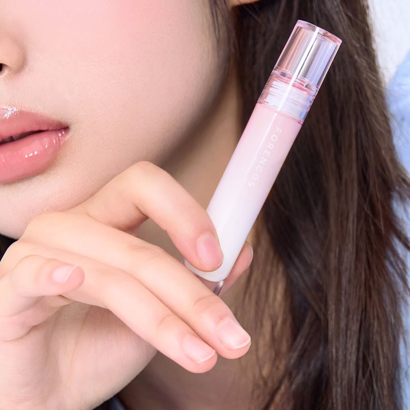 Close-up of a person holding FORENCOS All Light Mood Glow Tint next to their lips, showcasing the product design and color.