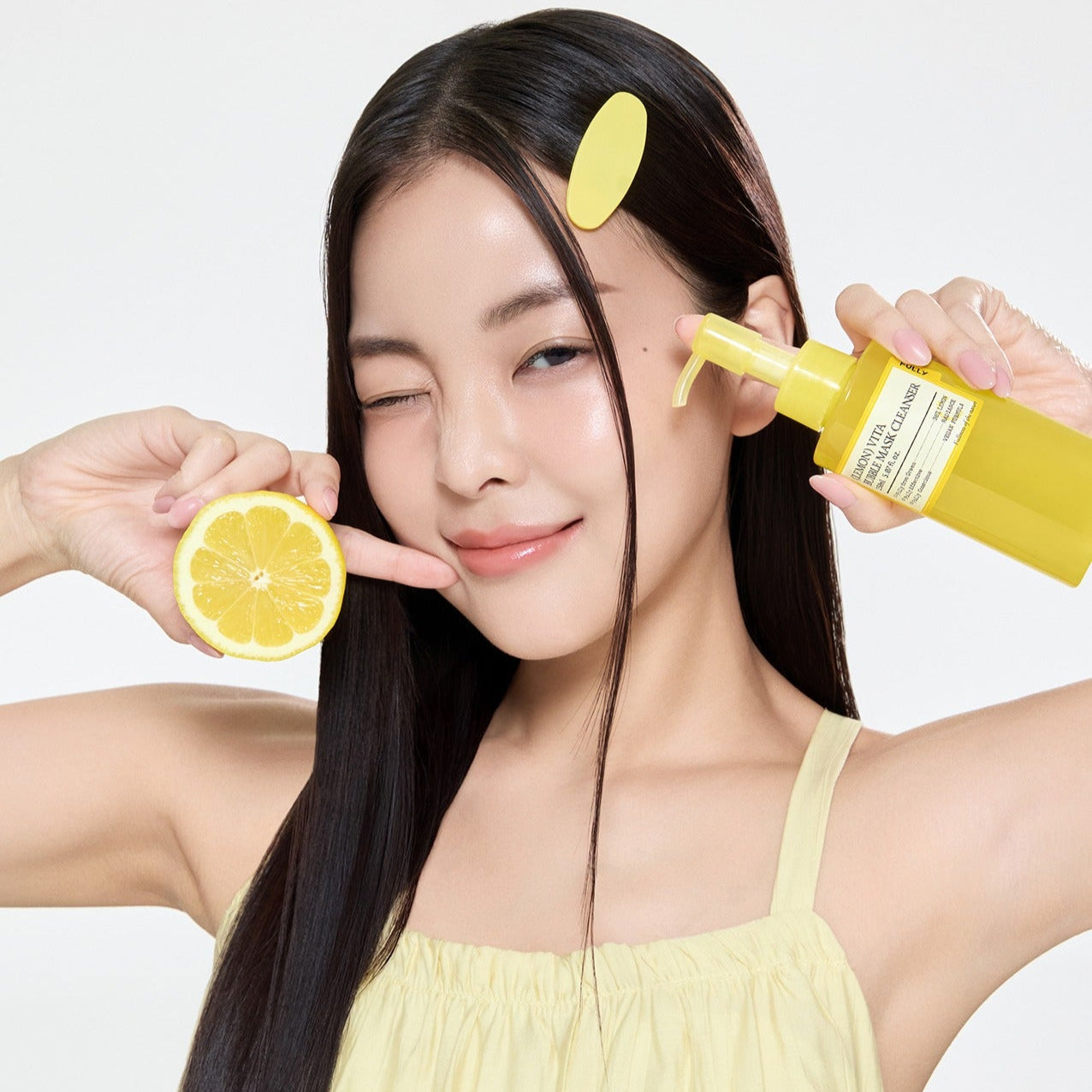 Woman holding FULLY Lemon Vita Bubble Pack Cleanser 150ml and a lemon slice, showcasing skincare product.
