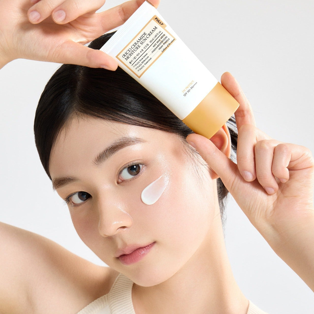 Woman applying FULLY Rice Sera Moisture Sunscreen 50ml to her face