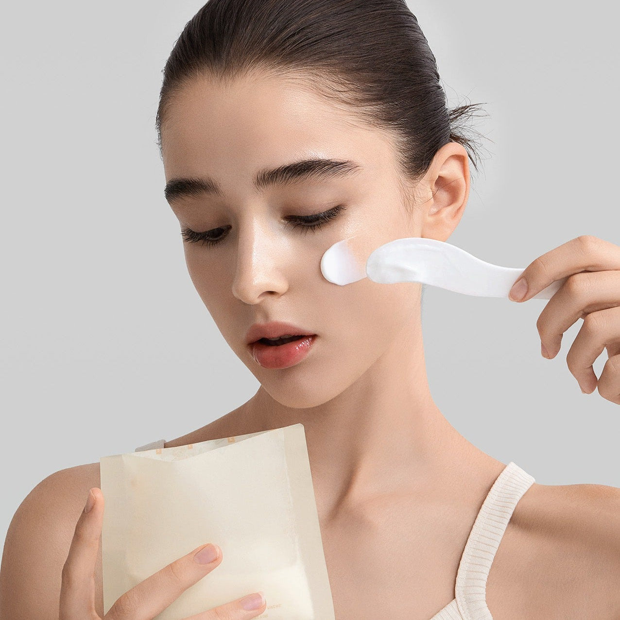 Woman applying FULLY Rice dough modeling mask 4ea with spatula on her face for skincare routine.
