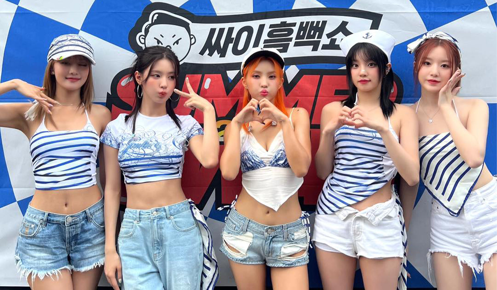 Group of young women posing in front of a colorful summer event backdrop, wearing blue and white coordinated outfits.