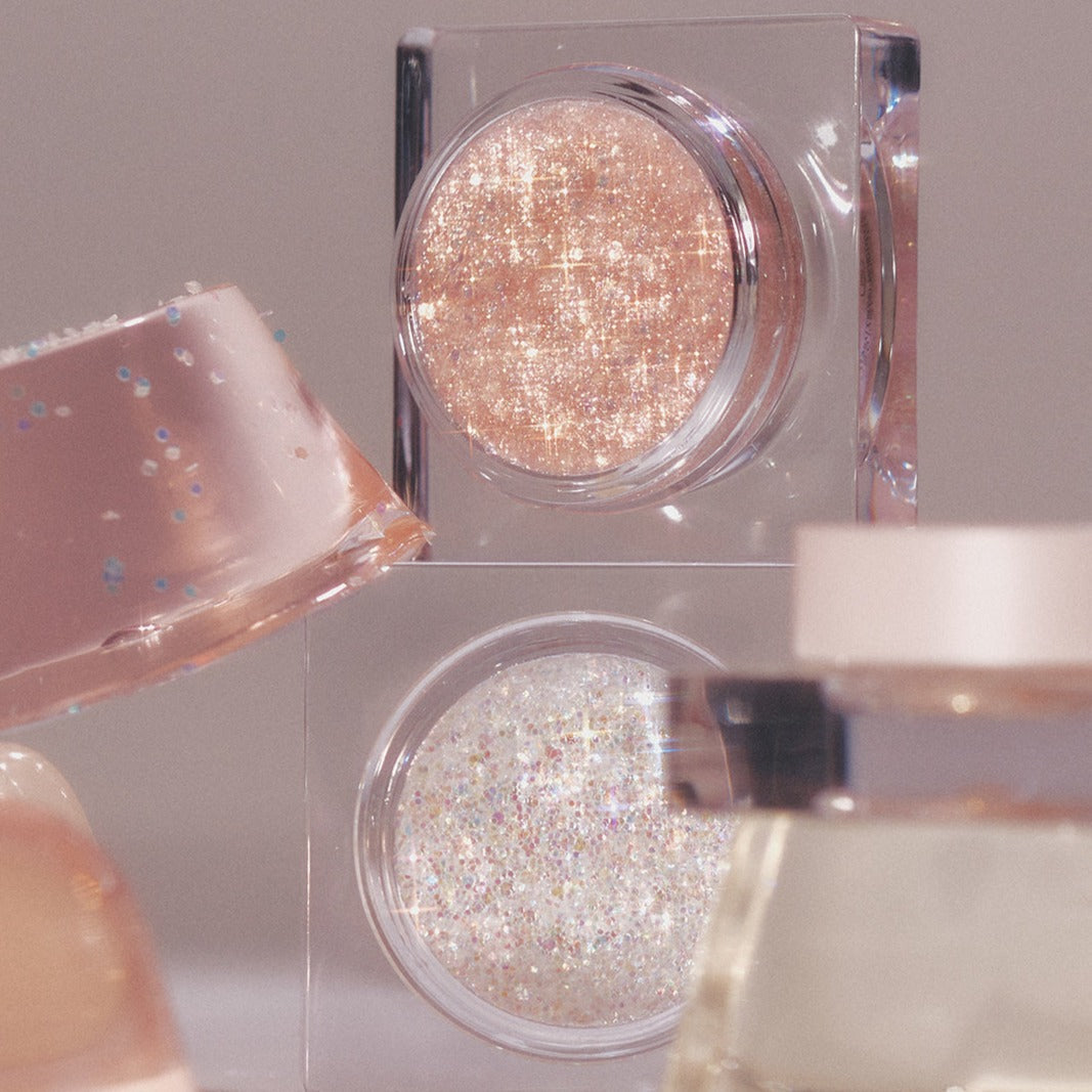 Close-up of GLINT Glitter Gel in shimmering pink and white shades, perfect for adding sparkle to your makeup collection.