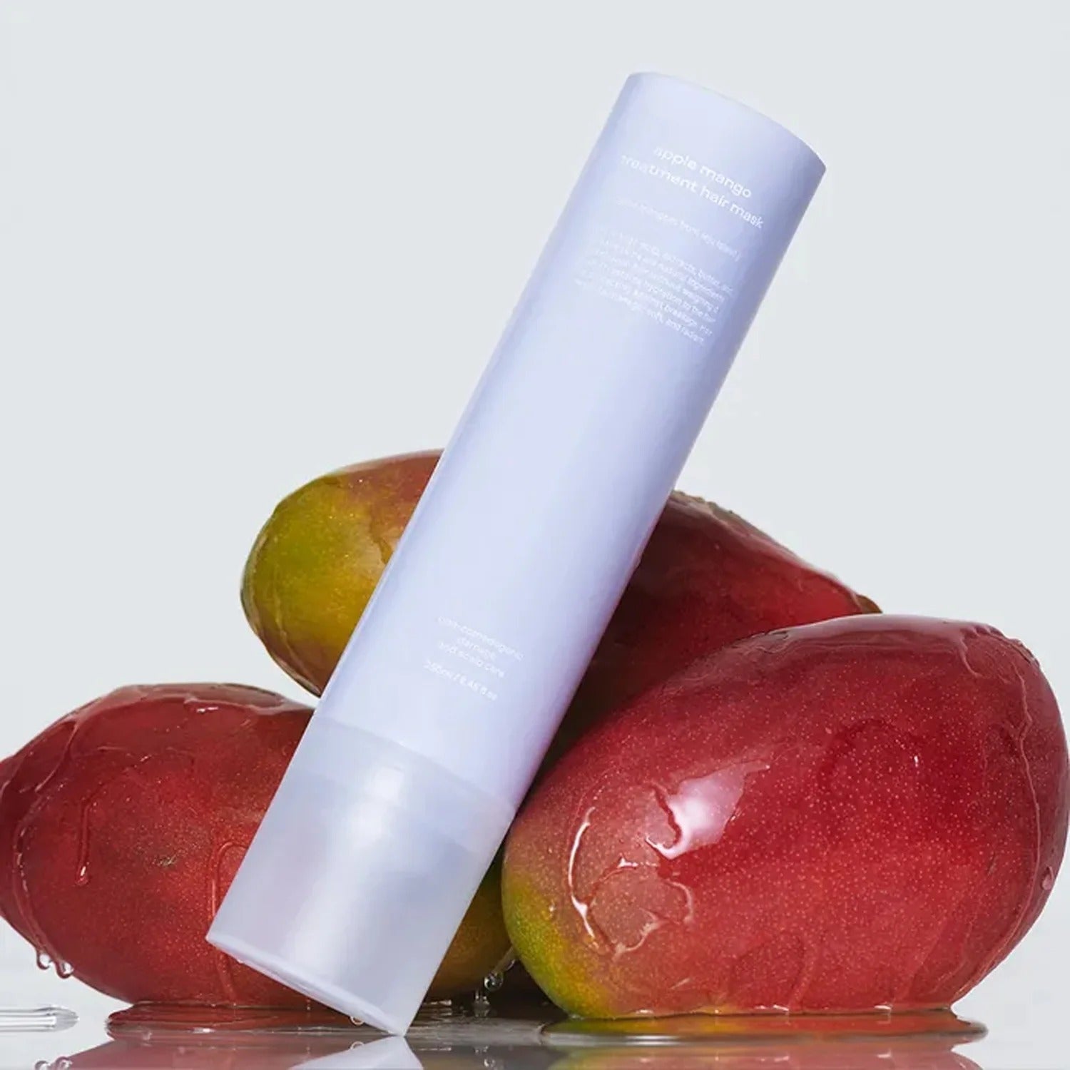 GLOW Apple Mango Hair Treatment 250ml bottle with fresh mangos in the background