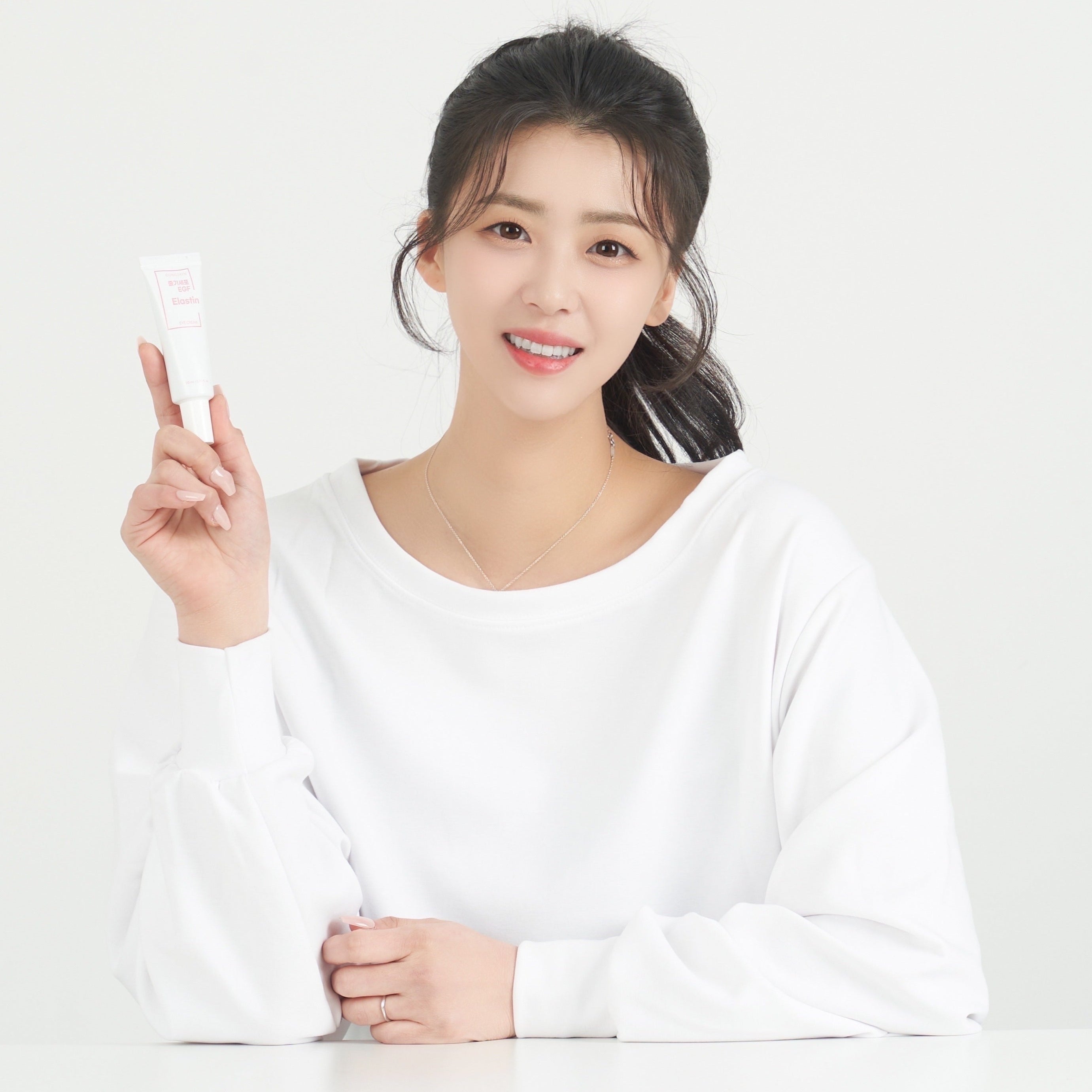 Person holding GONGSKIN Stem Cell EGF Elastin Eye Cream 20ml tube, smiling and wearing white shirt.