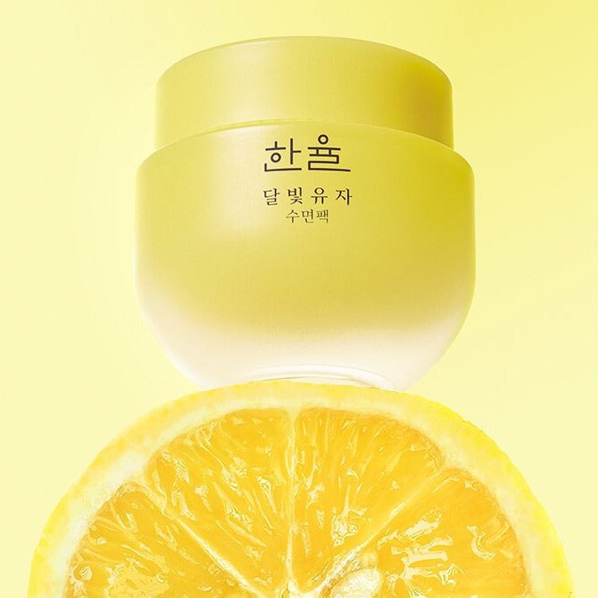 HANYUL Yuja Sleeping Mask 70ml jar with yuja fruit backdrop, bright yellow packaging.