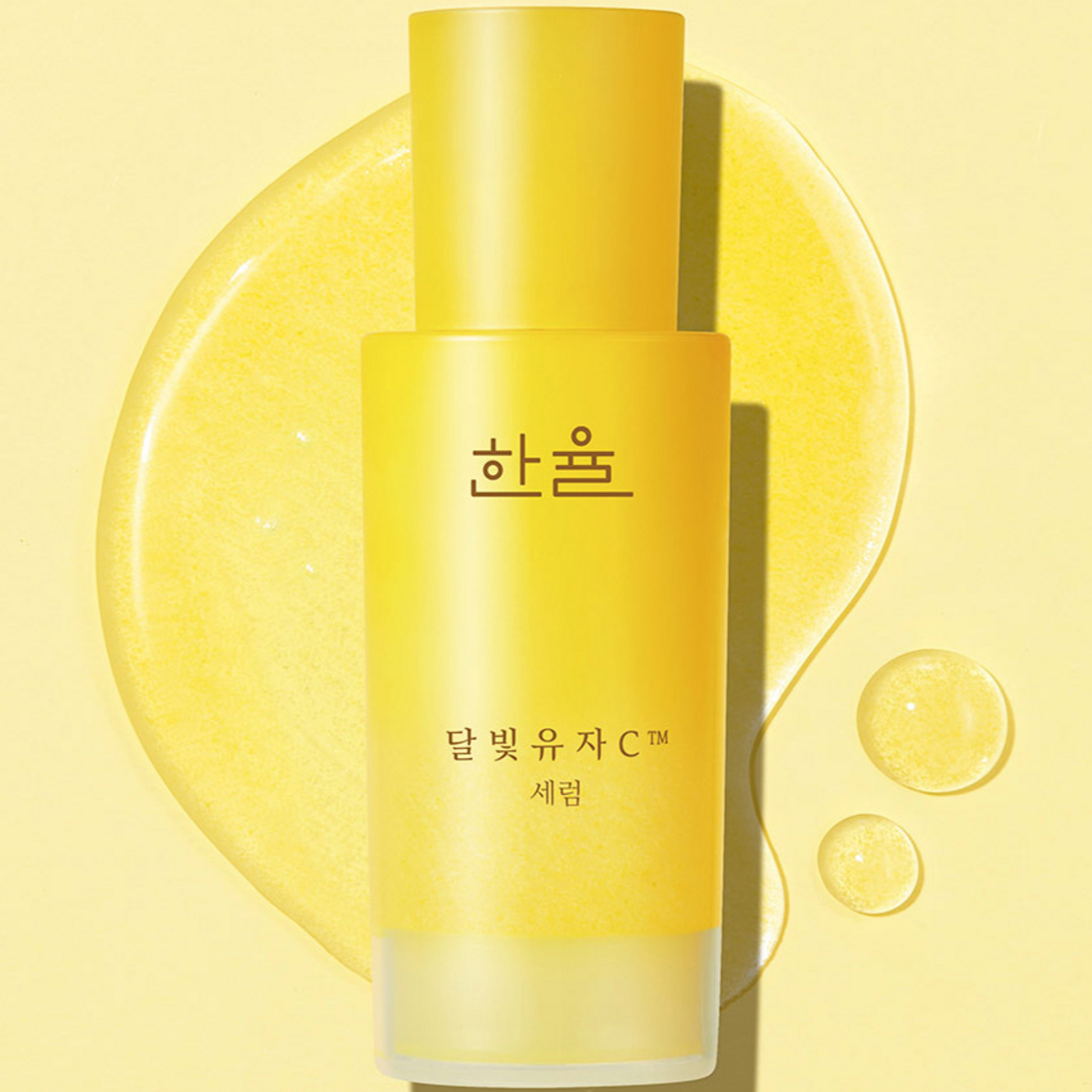 HANYUL Yuja Vitamin C Brightening Serum 50ml in a yellow bottle with liquid highlights on a bright yellow background.