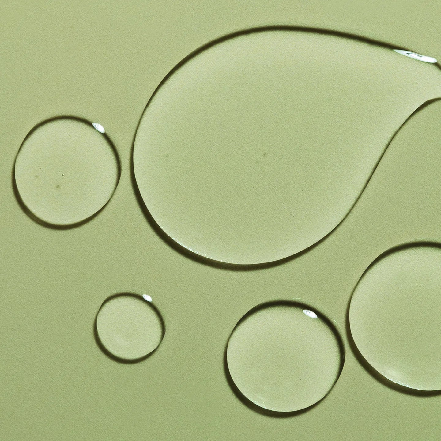 Droplets of HARU HARU Black Rice Hyaluronic Toner Unscented 150ml on a green background.
