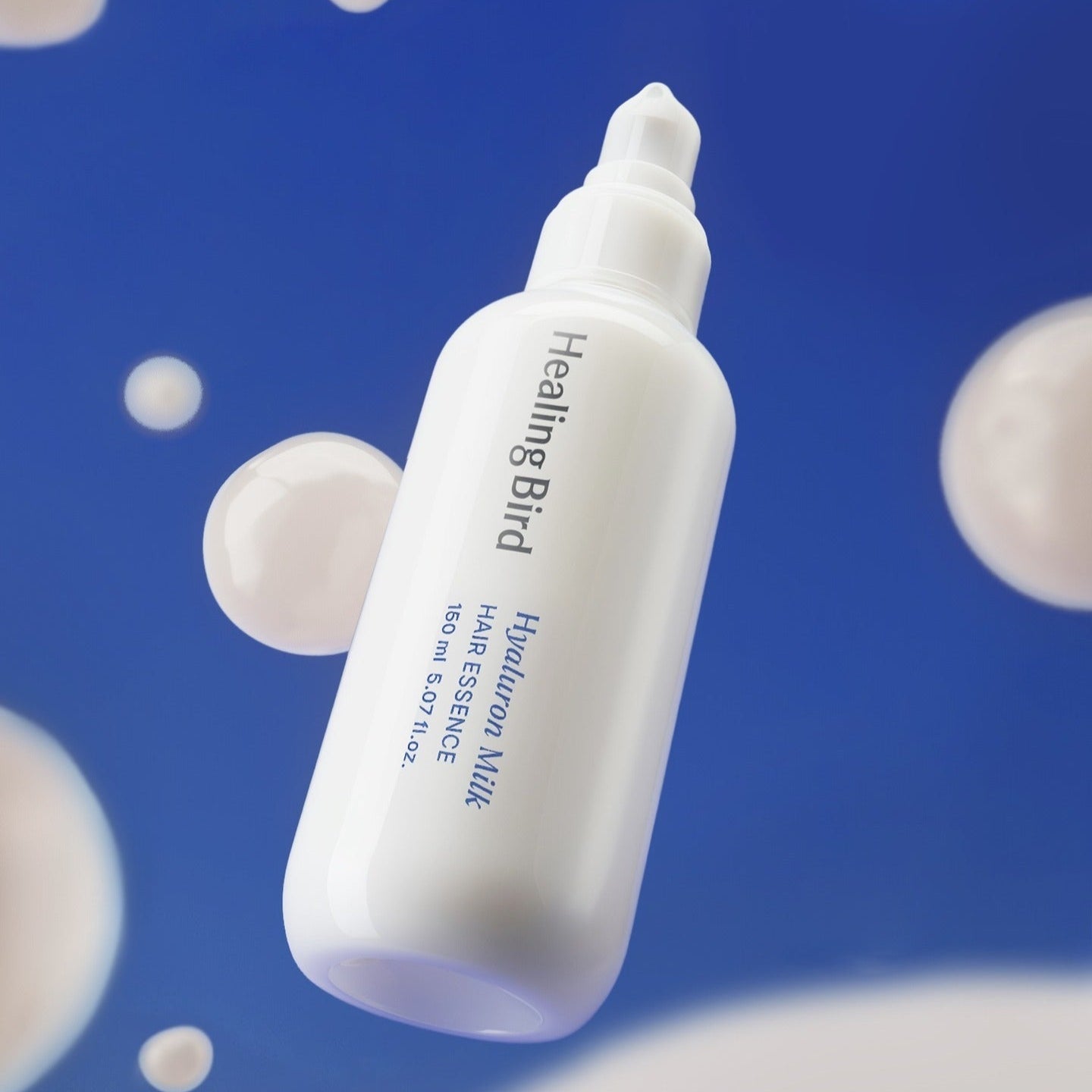 HEALING BIRD Hyaluronic Milk Hair Essence 150ml bottle image against a blue background with bubbles.