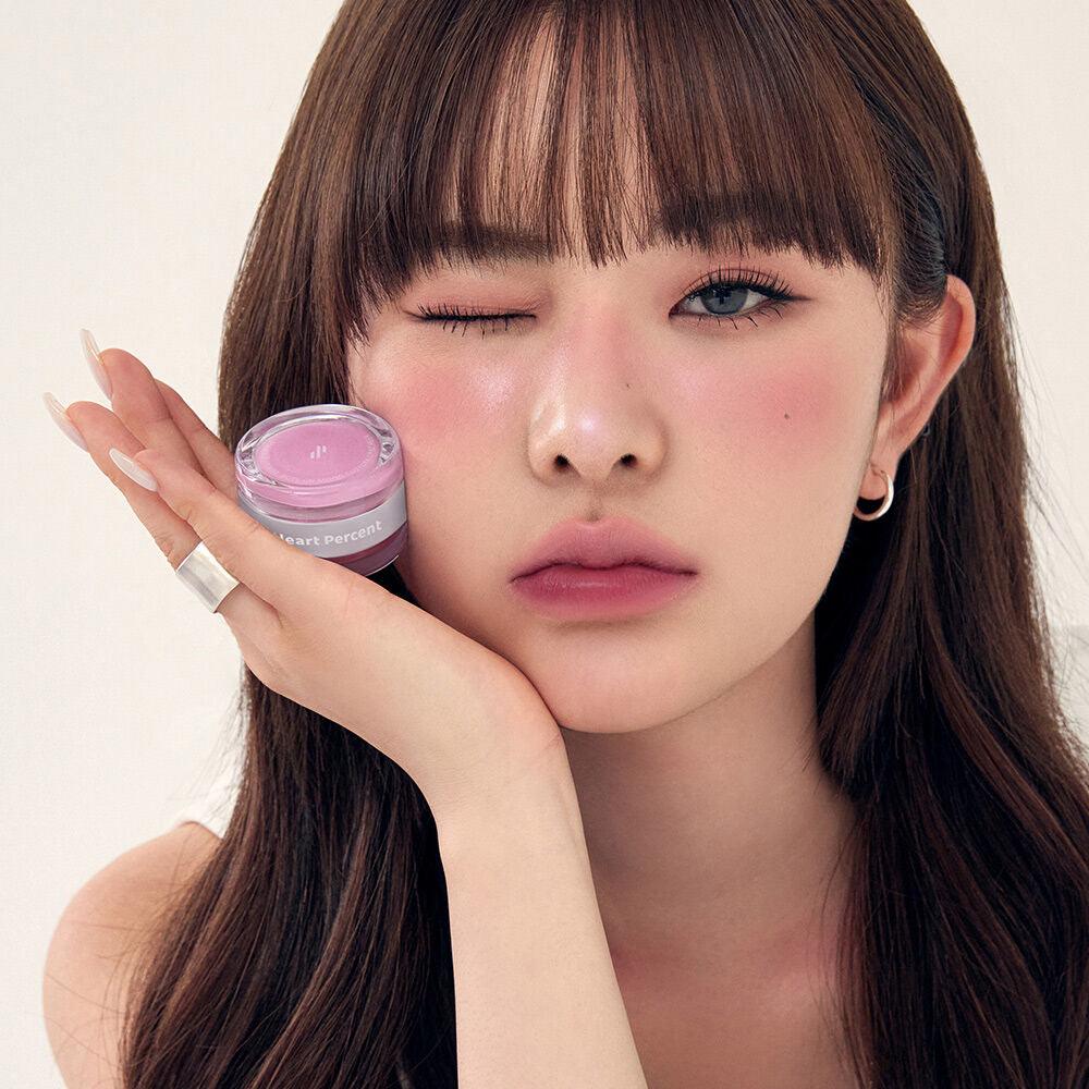 Woman holding HEART PERCENT Dot On Mood Custom Lip & Cheek, showcasing lip and cheek color in a stylish setting.