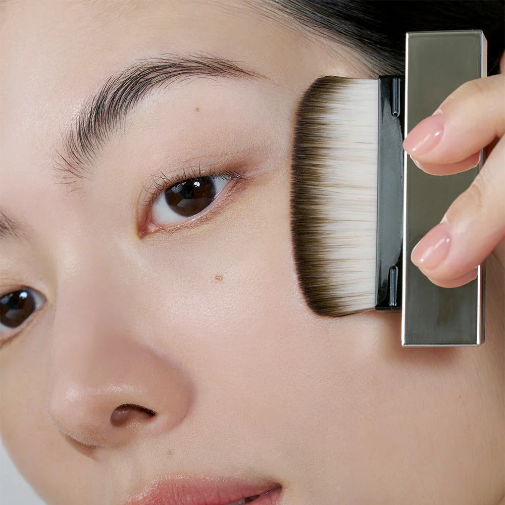 Applying makeup with HERA Airy Powder Primer 8.5g brush on cheek for smooth skin finish.