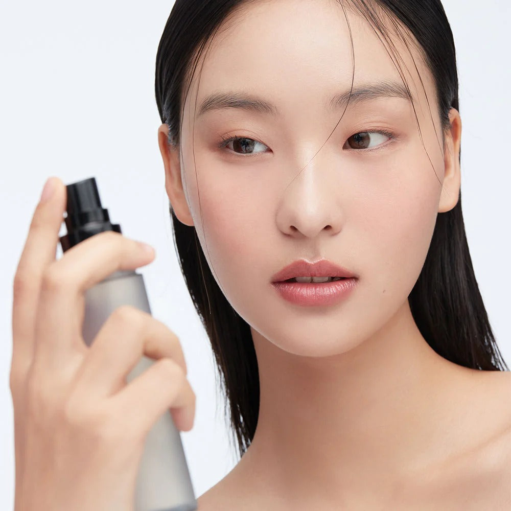 Woman using HERA Make Up Fixer 80ml for a flawless finish.