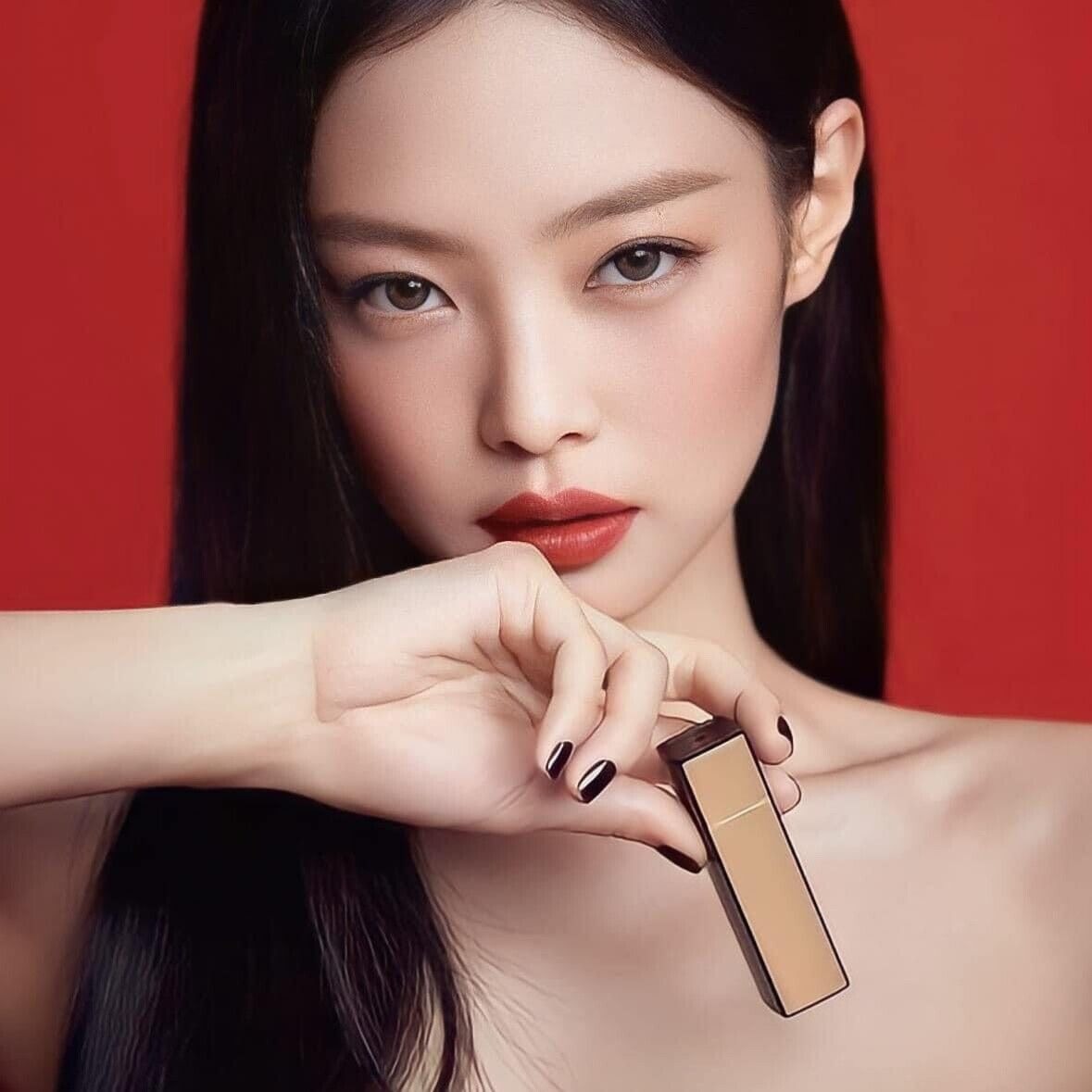 Model holding HERA Rouge Clasyy 3.5g lipstick with bold red color against a red background.