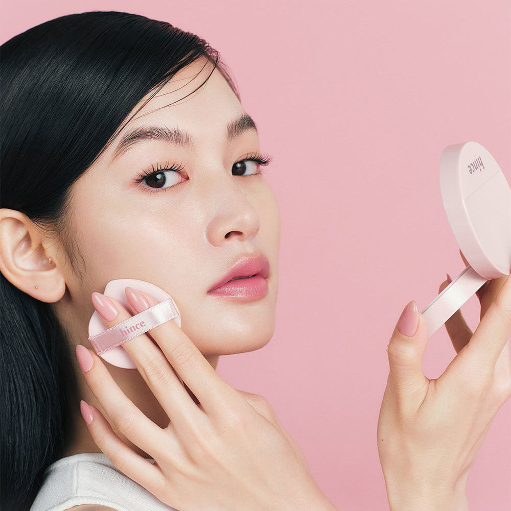 Model applying HINCE Cover Master Pink Cushion on face, showcasing radiant finish and smooth application for flawless skin.