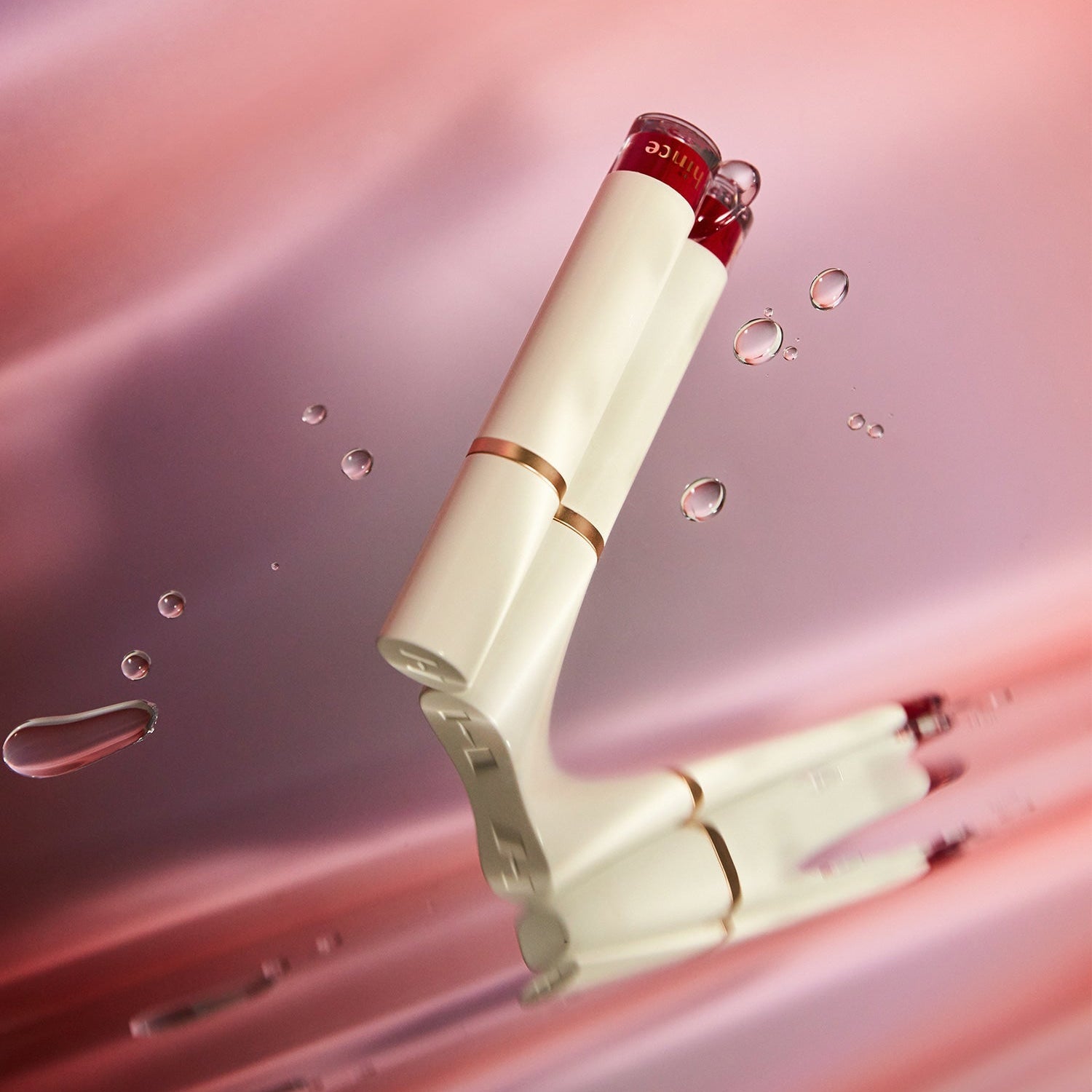 HINCE Mood Enhancer Water Liquid Glow product on a pink background with water droplets.