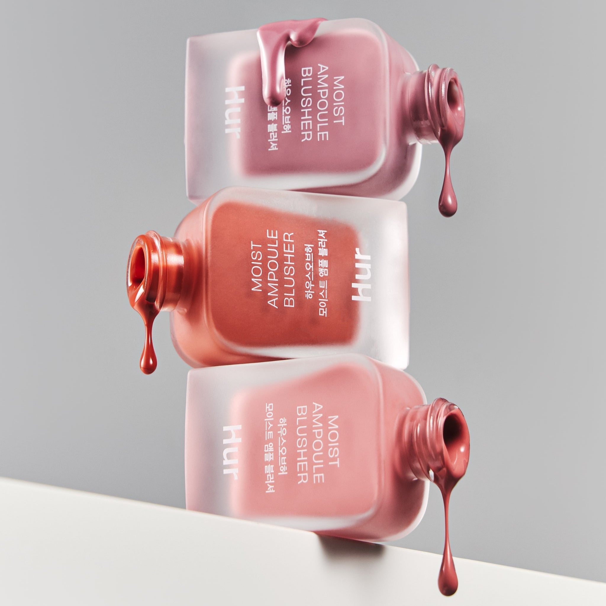 HOUSE OF HUR Moist Ampoule Blusher 10ml bottles with rich, creamy texture in assorted shades spilling artistically on a reflective surface.