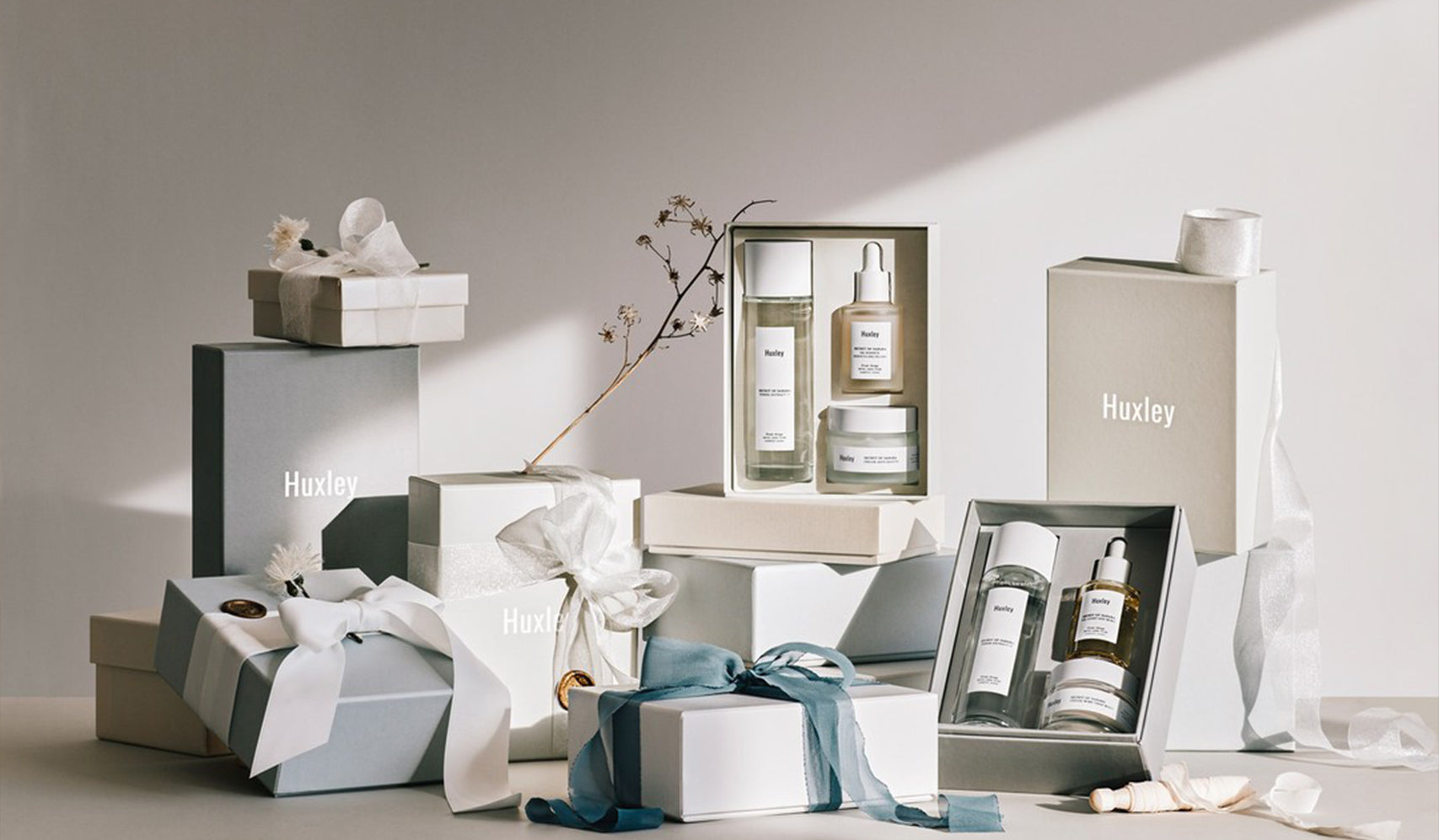Huxley skincare products elegantly displayed in gift boxes with ribbons and minimalist decor.