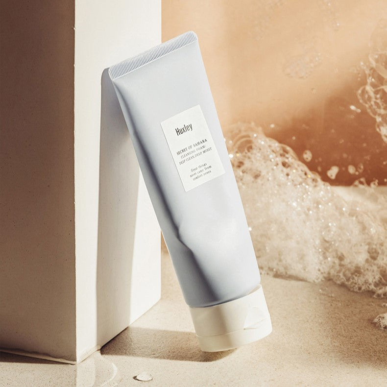 HUXLEY Cleansing Foam Deep Clean Deep Moist 150g in a bathroom setting with bubbles in the background.