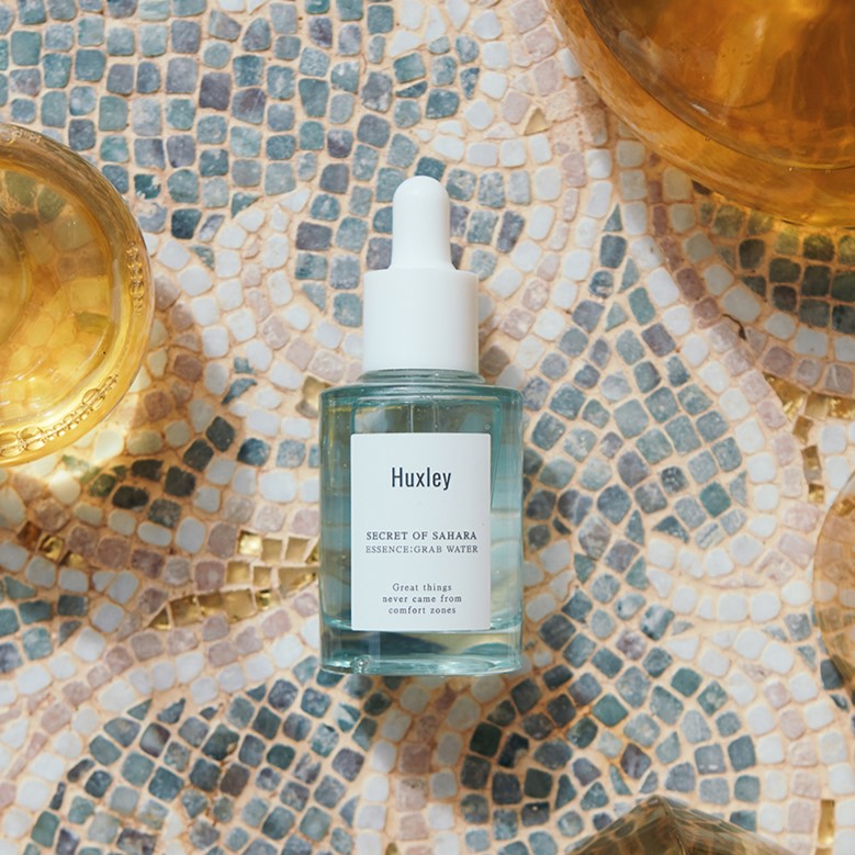 HUXLEY Essence Grab Water 30ml product on mosaic background, 30ml bottle with dropper cap, enhances skincare routine