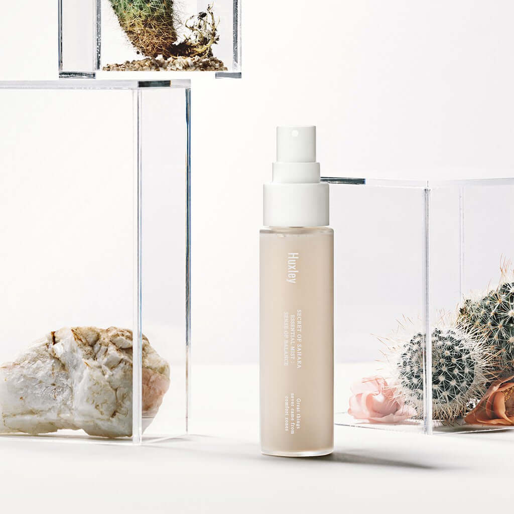 HUXLEY Essential Mist Sense Of Balance hydrating mist bottle amid cacti background.