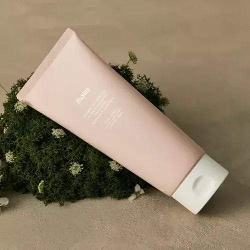 HUXLEY Intense Moisture Treatment Moroccan Gardener tube placed on green foliage for skincare hydration and nourishment.