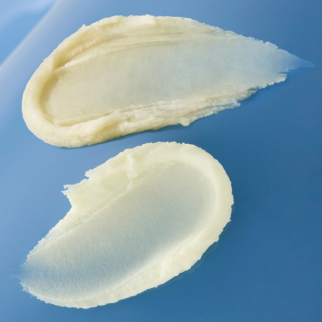 Texture of HUXLEY Sun Stick Watery Touch 20g showing creamy application on a blue background.