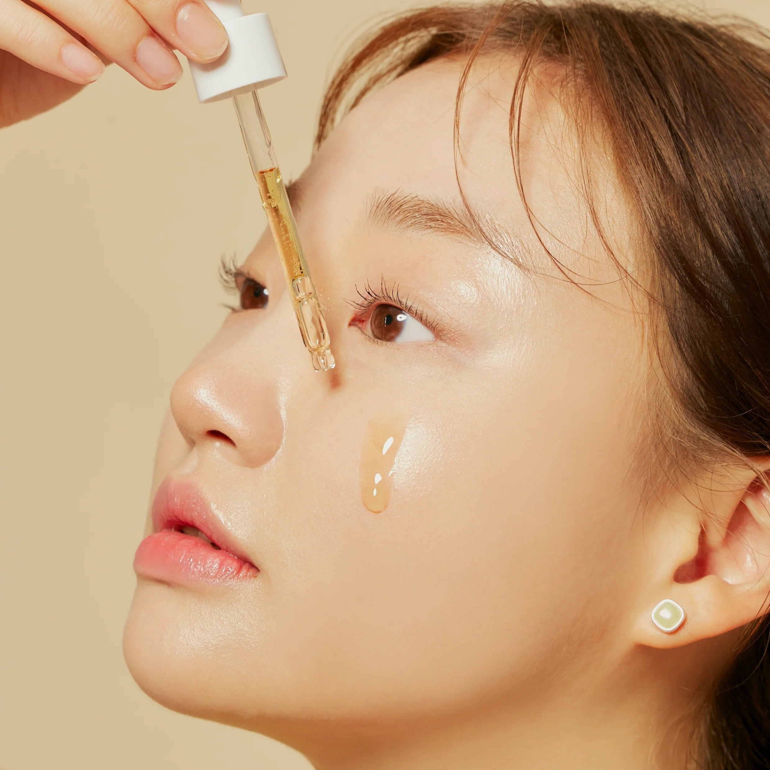 Woman applying HYGGEE Own Vegan Calming Serum 50ml to her face with dropper, showcasing skincare application and hydration.
