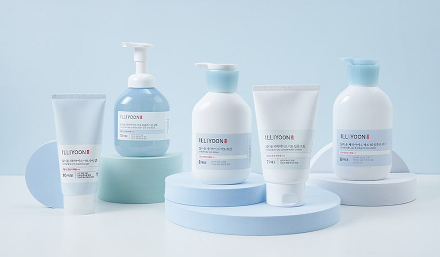 Skincare products displayed on pastel blue and white platform, featuring tubes and bottles for a refreshing beauty routine.