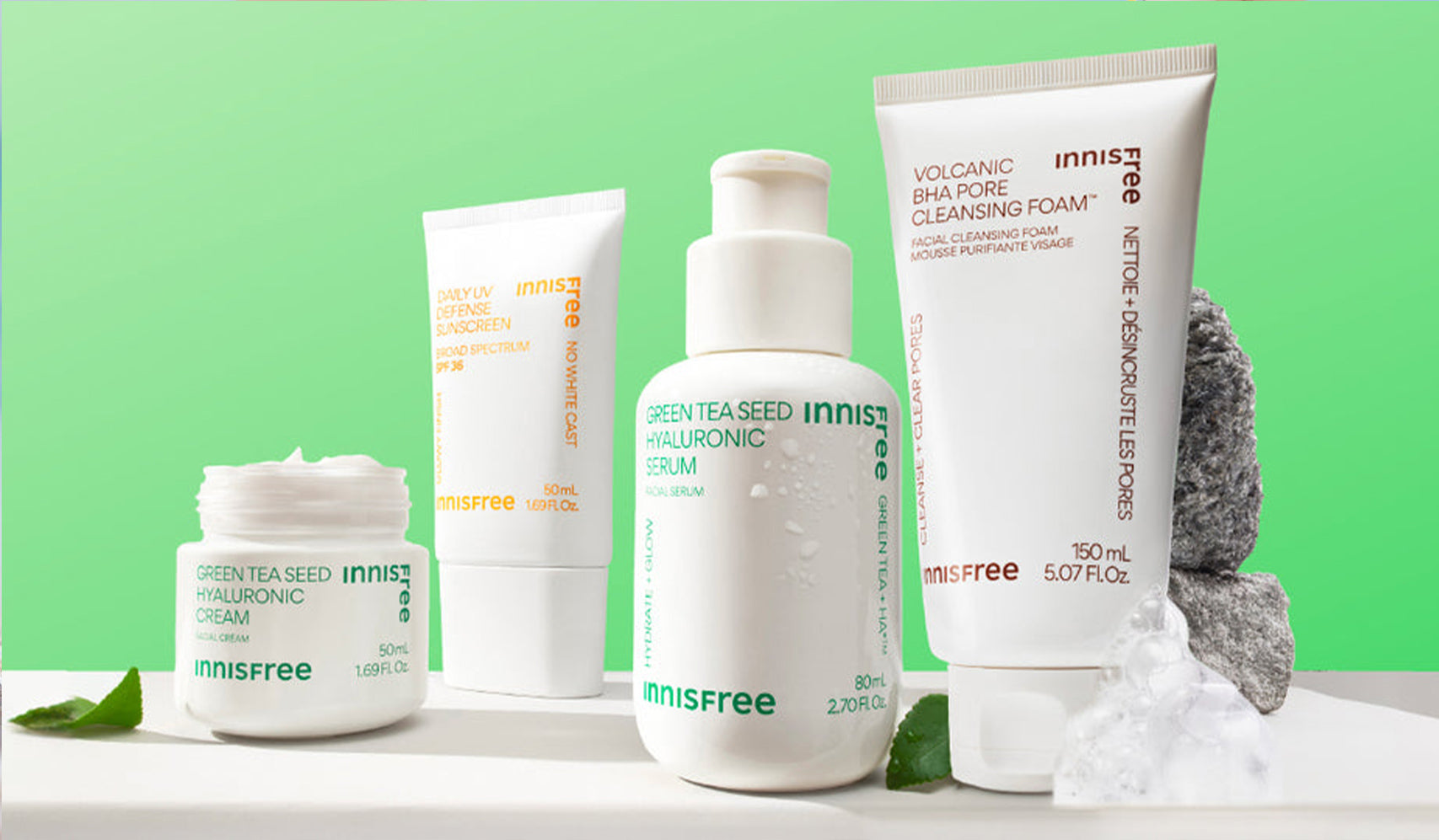 Innisfree skincare products including green tea seed hyaluronic serum and volcanic pore cleansing foam on a green background.