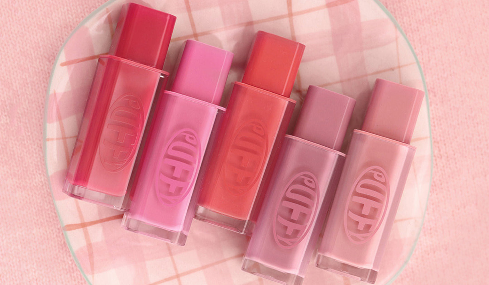 Assorted pink gradient lipsticks on a pastel checkered background