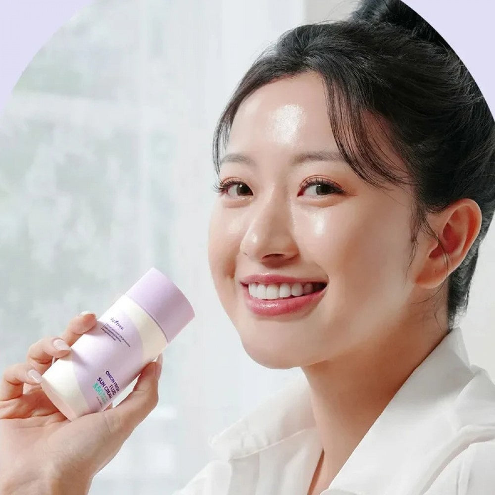 Smiling person holding ISNTREE Onion fresh Fluid Sun Cream 50ml showcasing skincare product.