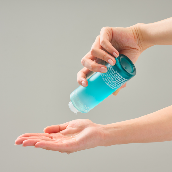 Person using ISOI Pore Tightening Tonic Essence 130ml on their hand.