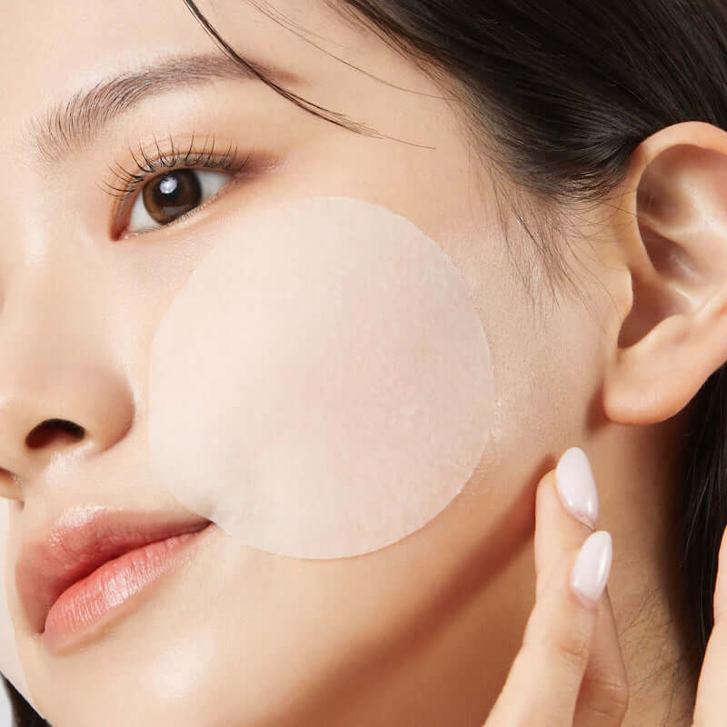 Woman using JUMISO Antioxidant Glow Toning Pads 70 Sheets on cheek for skincare routine