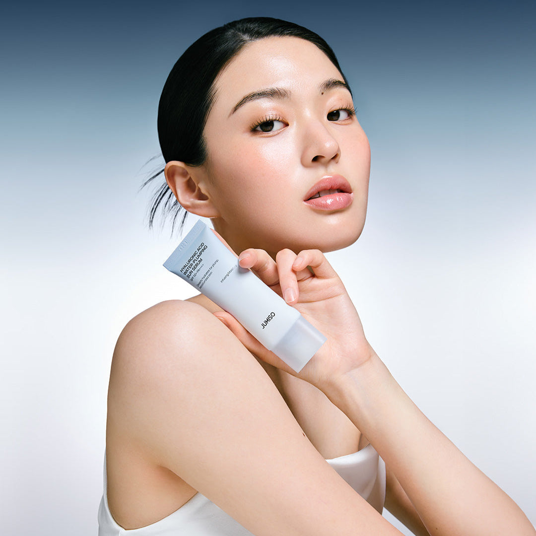 Model holding JUMISO Hyaluronic Acid Water Plumping Moisture Sun Serum 40ml against gradient background