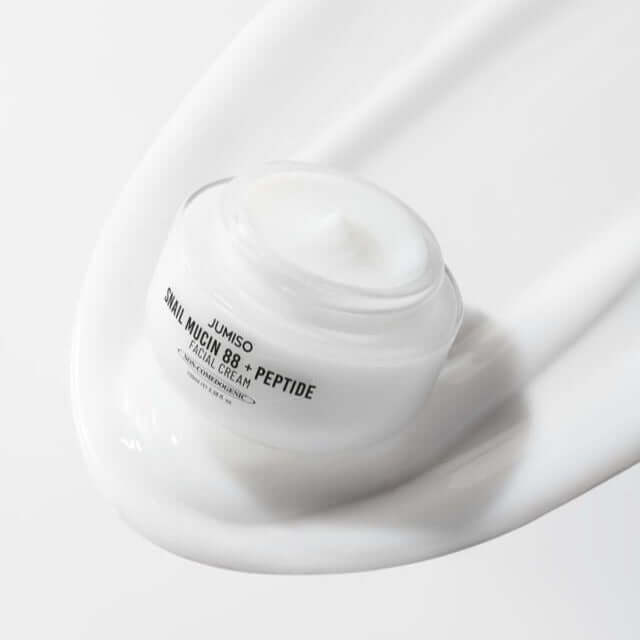 JUMISO Snail Muci 88 + Peptide Cream jar on a swirl of cream texture