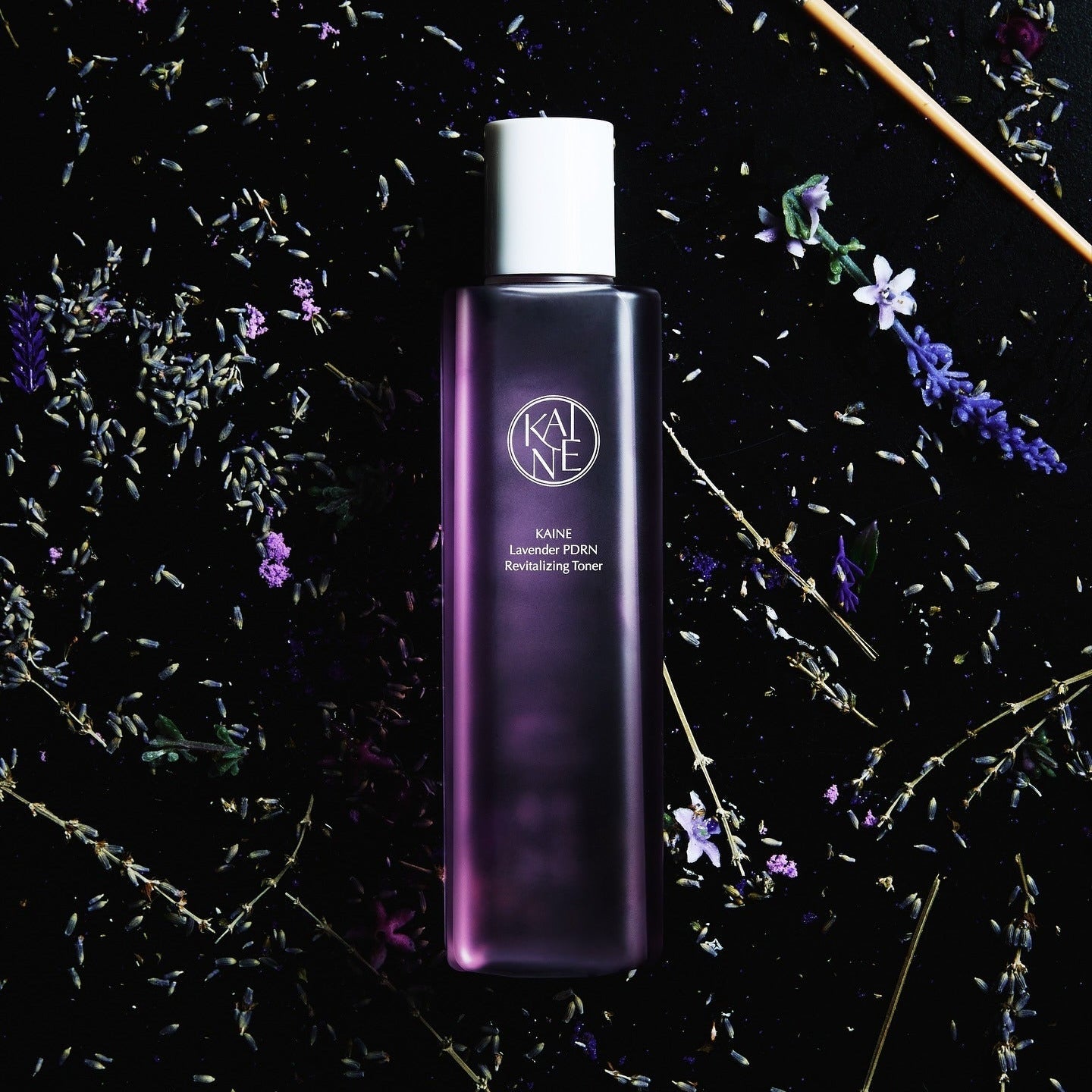 KAINE Lavender PDRN Revitalizing Toner 300ml bottle surrounded by lavender flowers on a dark background.