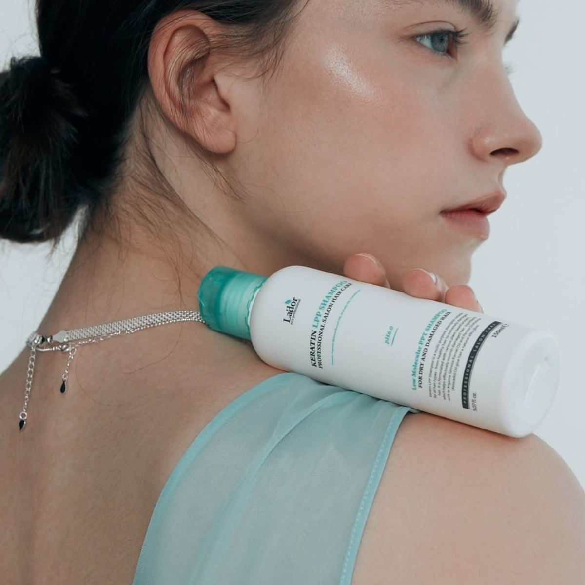 Woman holding LADOR Keratin LPP Protein Shampoo 150ml on shoulder