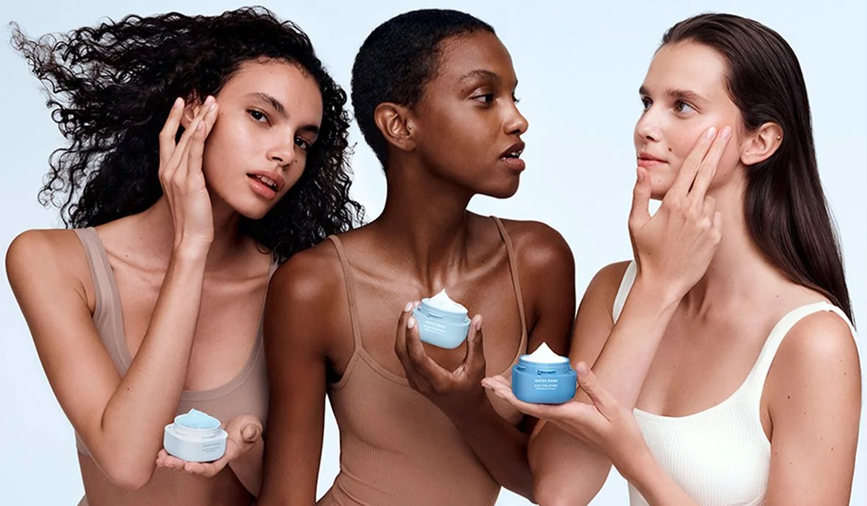 Three women applying blue moisturizing cream, promoting skincare routine.