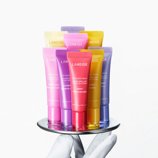 Assortment of LANEIGE Lip Glowy Balm 10g tubes in various colors displayed on a tray.
